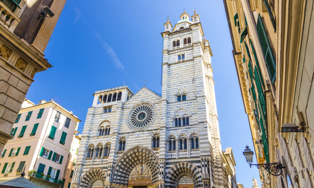 Facade of San Lorenzo Cathedral catholic church on Piazza San Lorenzo square among buildings in historical centre of old european city Genoa Genova with blue sky background, Liguria, Italy