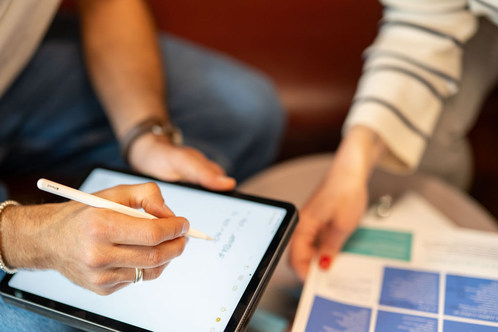 Two people are planning a travel with an Ipad and brochure.