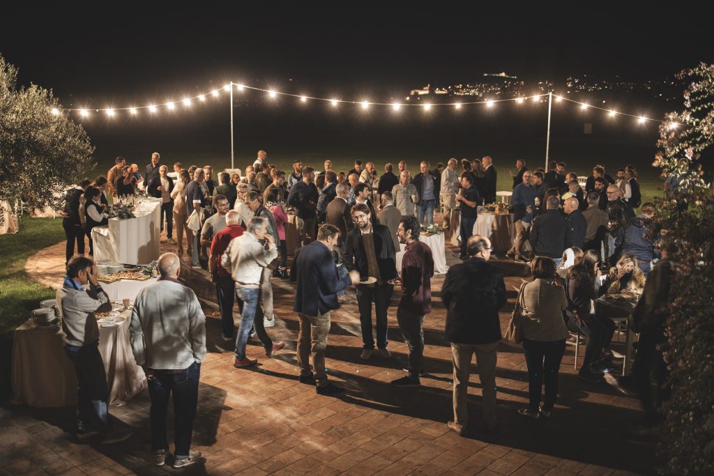 Group of people at a gathering, aperitif outside at night, lights.