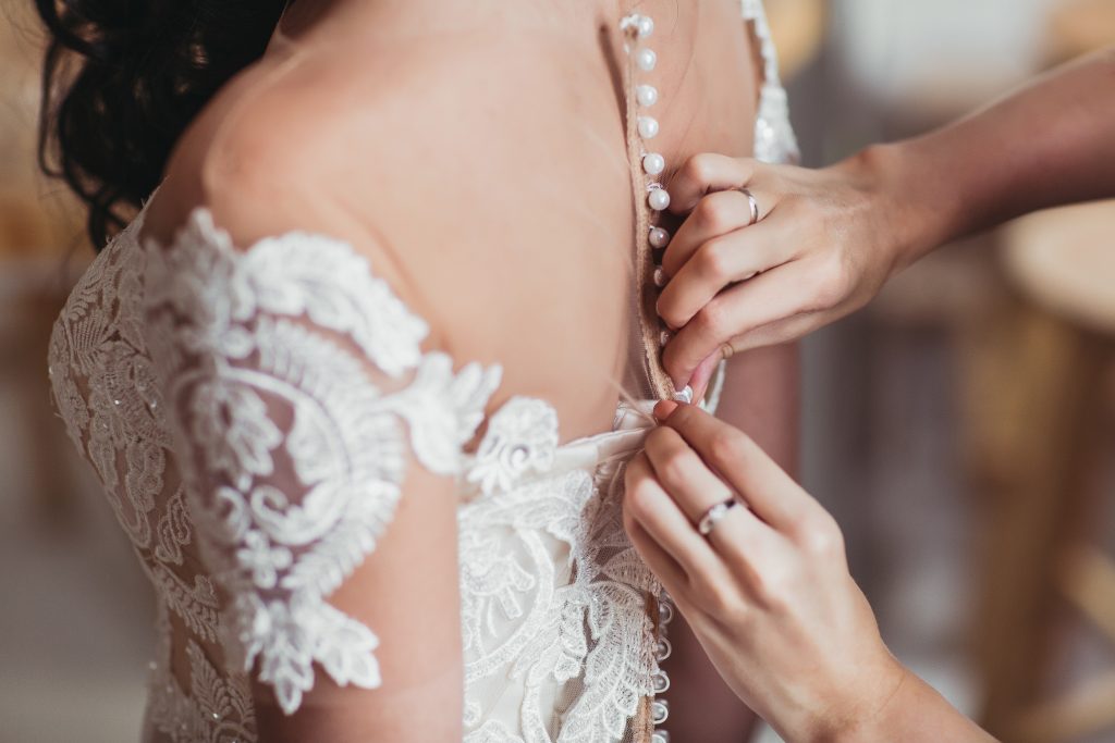 The bridesmaids helping to wear wedding dress for bride