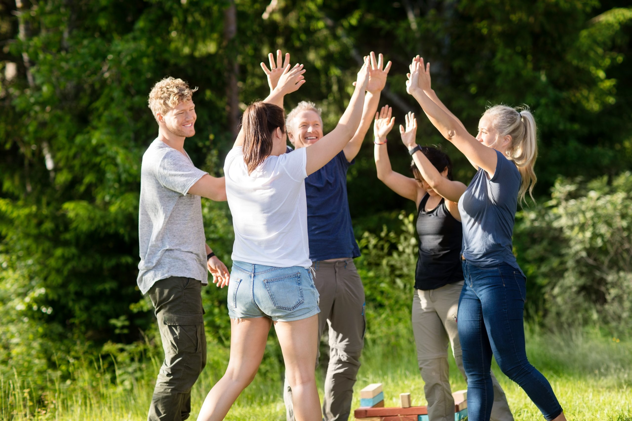 Team giving high-five, team activity outdoors.