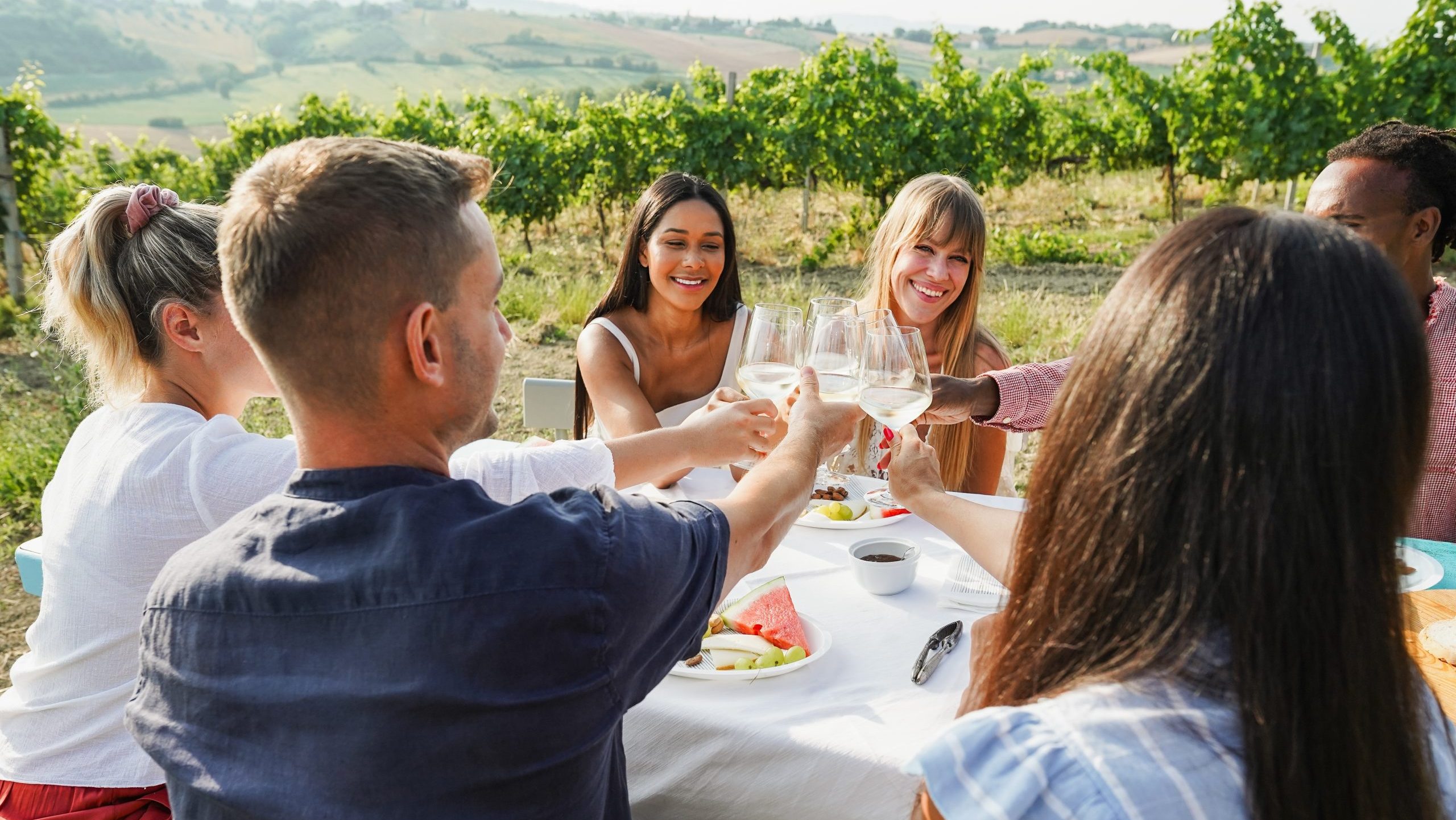 Freunde feiern draussen mit Essen und Wein.