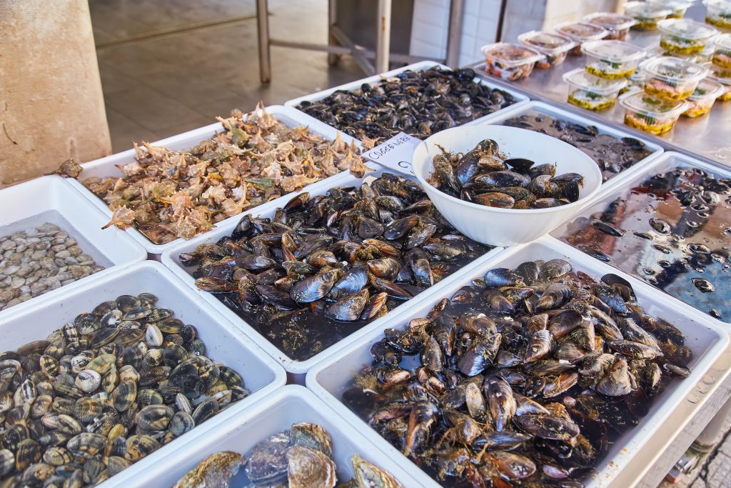 Muscheln und Meeresfrüchte auf Tabletts mit Preisschildern auf dem Straßenmarkt