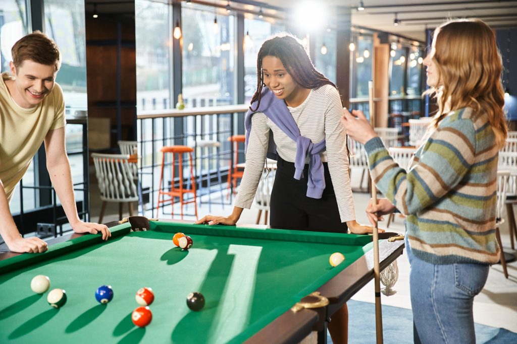 3 Teammitglieder spielen Billard in Co-Working Space.