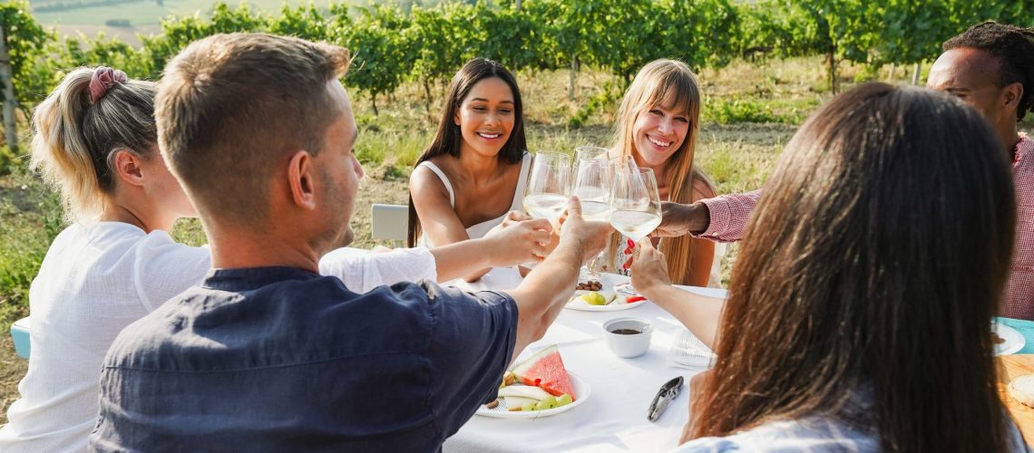 Freunde feiern draussen mit Essen und Wein.
