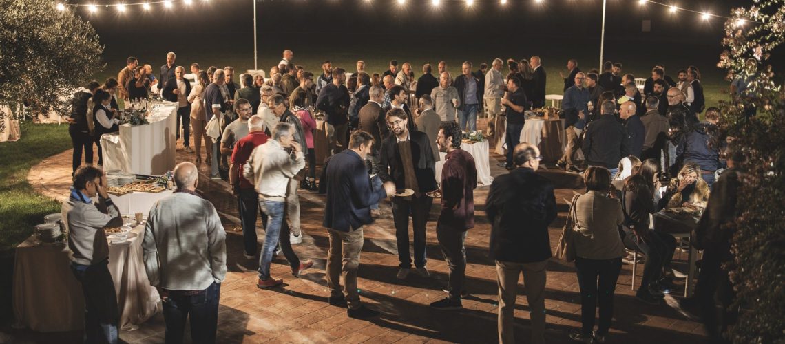 Group of people at a gathering, aperitif outside at night, lights.