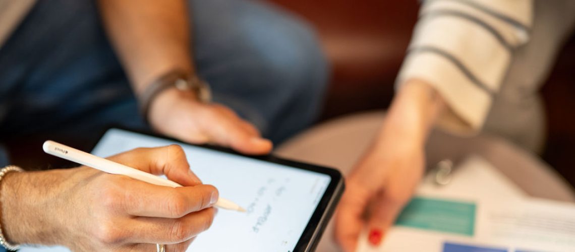 Zwei Leute sitzen in einer Besprechung mit einem Ipad.